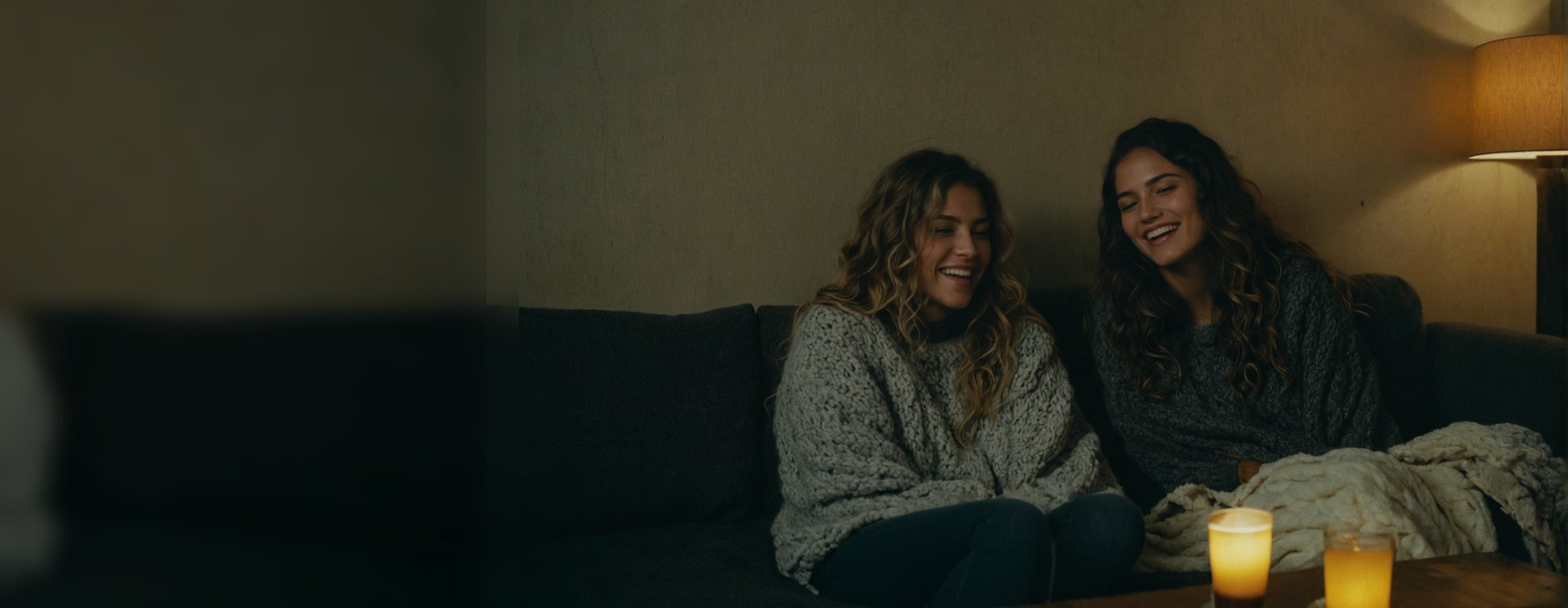 Two friends laughing together on the sofa during a movie night